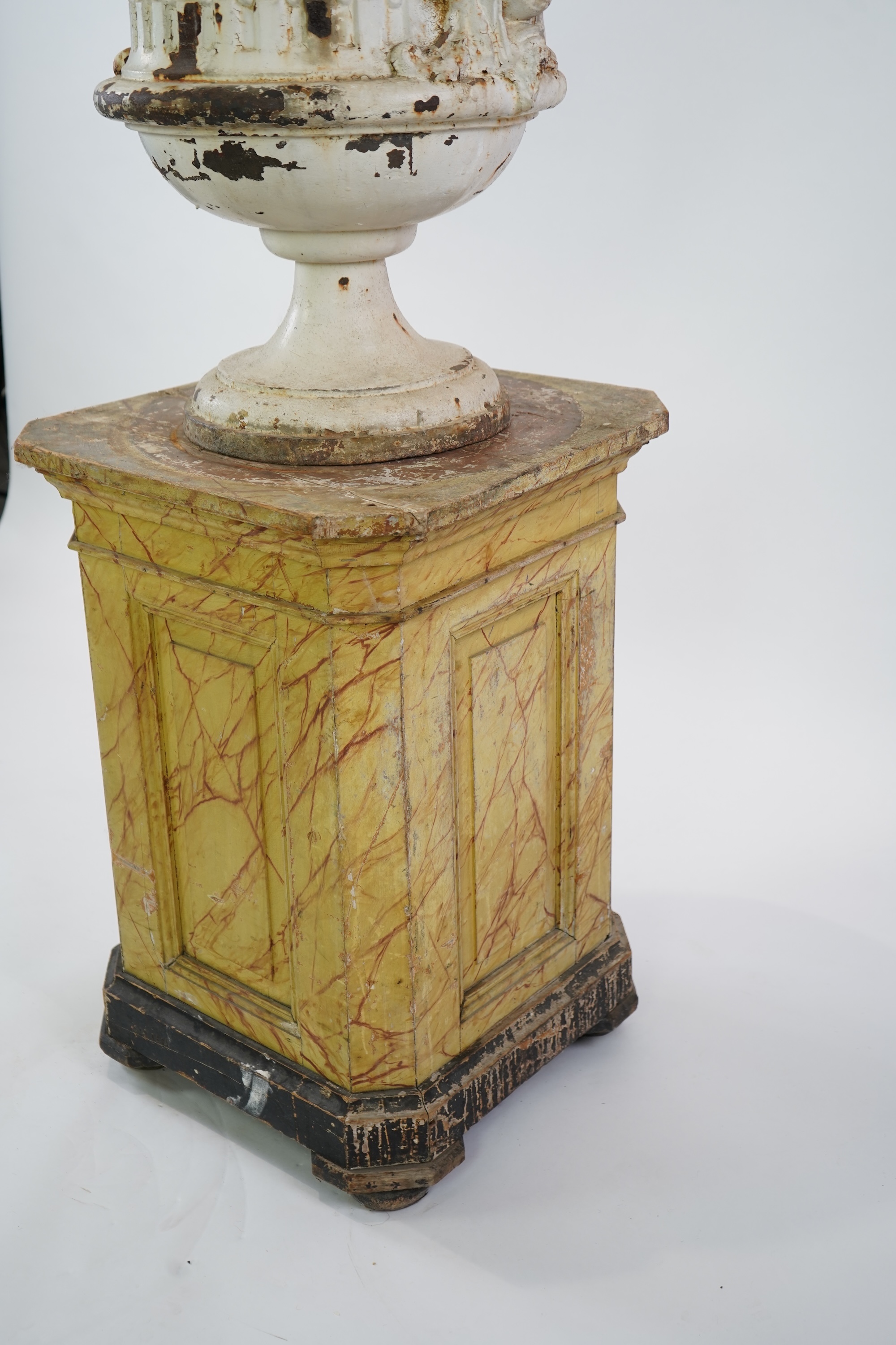 A Victorian white painted cast iron urn and a painted faux marble pedestal